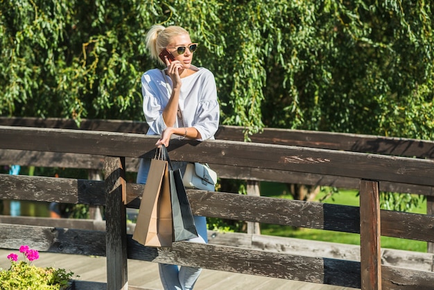 Lady talking on smartphone on footbridge