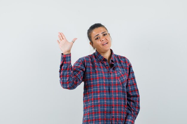 Lady waving hand in casual shirt and looking confident , front view.