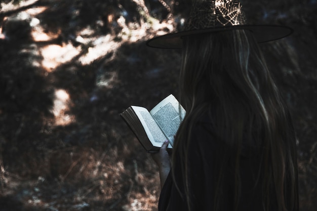 Free Photo lady in witch clothes reading book