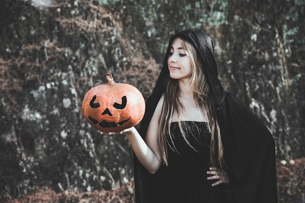 Lady in witch suit holding pumpkin