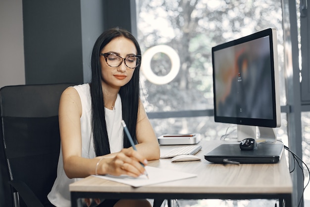 Lady with glasses. Manager is sitting at the computer. Businesswoman works in her office.