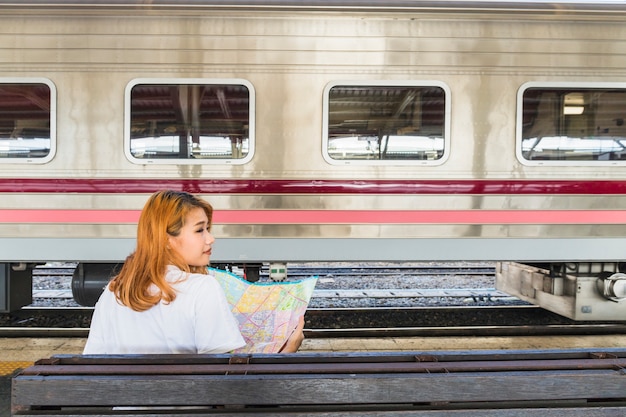 Free photo lady with map on seat near train on platform