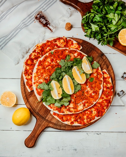 Free Photo lahmajun with meat a slice of lemon herbs on a round board