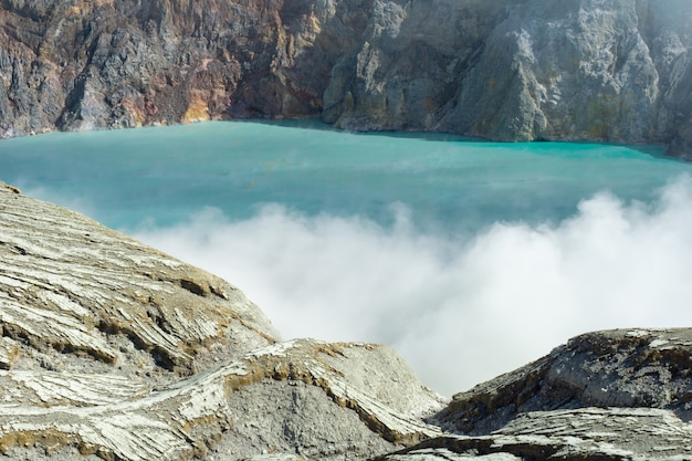 Lake expelling smoke surrounded by rocks