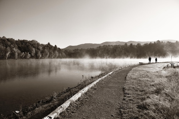 Lake fog in park with Autumn foliage and mountains with reflection in New England Stowe