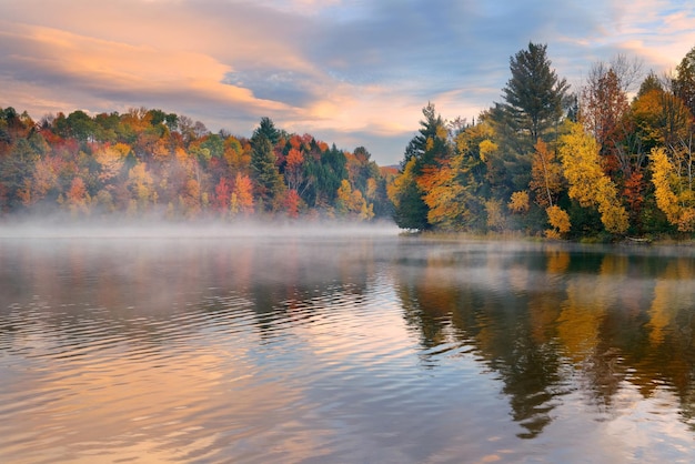 Lake fog sunrise with Autumn foliage and mountains in New England Stowe