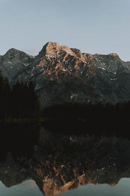 Free photo lake surrounded by mountains with trees reflecting on the water at daytime