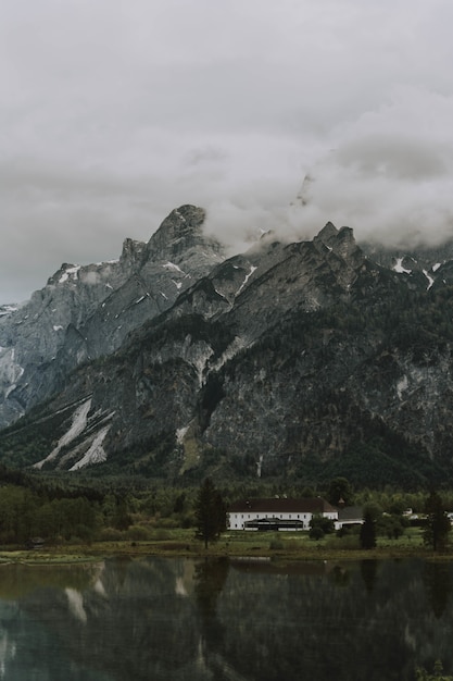 Free Photo lake surrounded by trees and rocky mountains covered in the fog under a cloudy sky