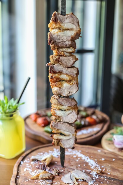 Lamp kebab skewer on the wooden board salt pepper lemonade side view