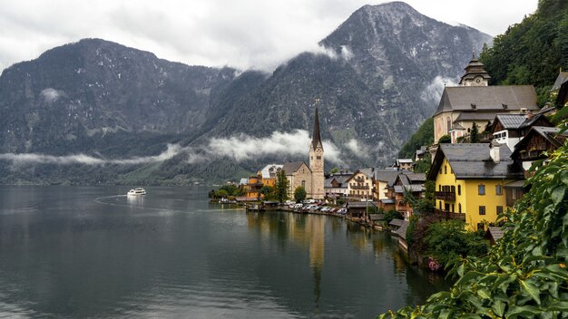 Landscape of Hallstatt surrounded by water and rocky mountains during a rainy day in Austria