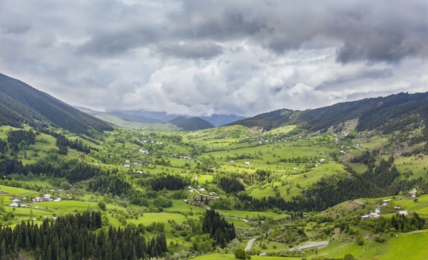 Landscape of hills covered in buildings and forests under a dark cloudy sky