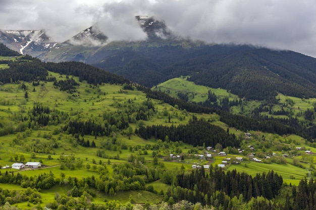 Landscape of hills covered in forests snow and fog under a cloudy sky at daytime