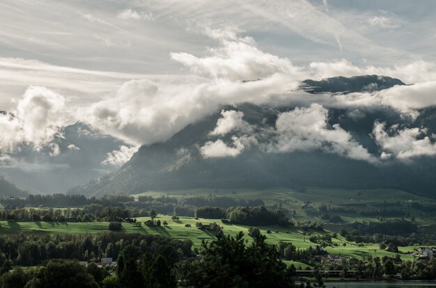 Landscape of hills covered in greenery and fog under the sunlight and a cloudy sky