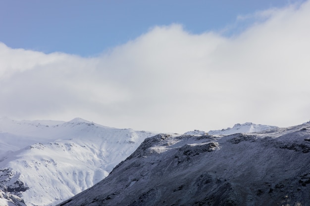 Landscape of mountains covered in the snow under a blue cloudy sky in Iceland