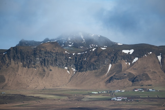 Free photo landscape of mountains covered in the snow and grass under a cloudy sky in iceland