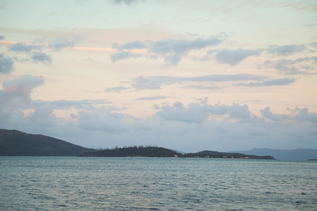 Landscape of the sea surrounded by hills covered in greenery under a cloudy sky