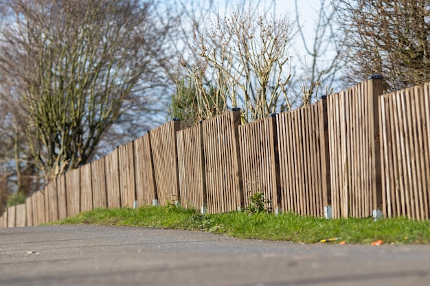 Landscape shot of a brown wooden fence of a mini forest with a clear blue sky