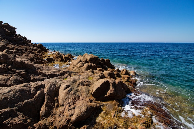 Landscape shot of large bedrocks in an open blue sea with a clear sunny blue sky