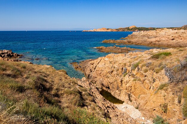 Landscape shot of rocky hills in an open blue ocean with a clear blue sky