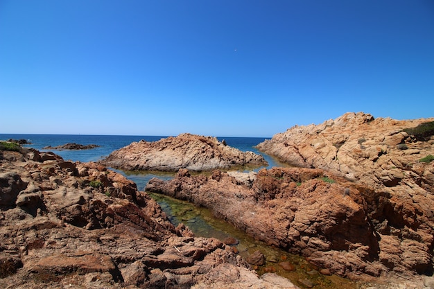 Free Photo landscape shot of seashore with big rocks in a clear blue sky