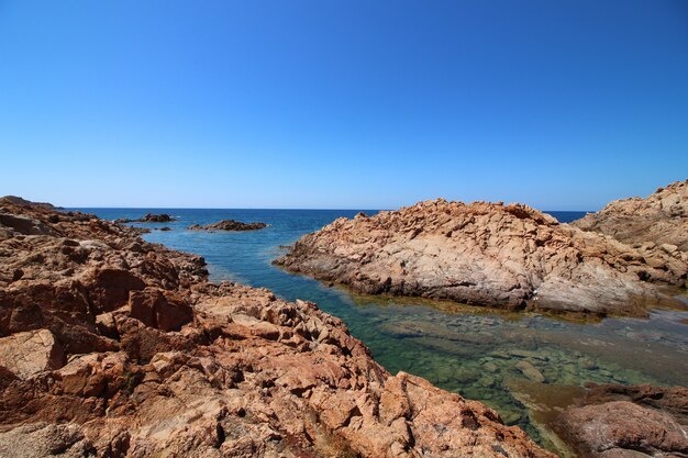 Landscape shot of a seashore with big rocks in a clear blue sky