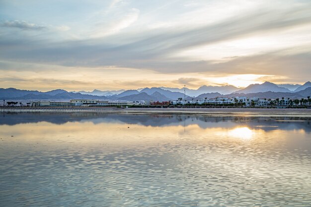 The landscape sky is reflected in the sea with lone figures in the distance.