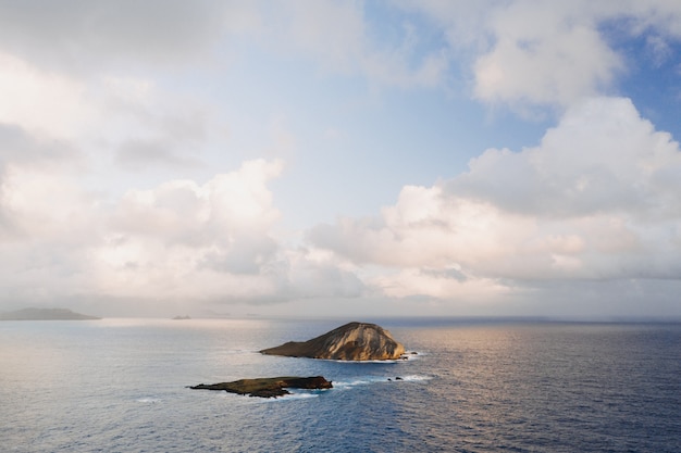 Landscape of a small island surrounded by the sea under a cloudy sky and sunlight