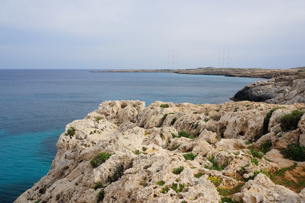 Landscape view of the rocky shore of the ocean under the blue sky