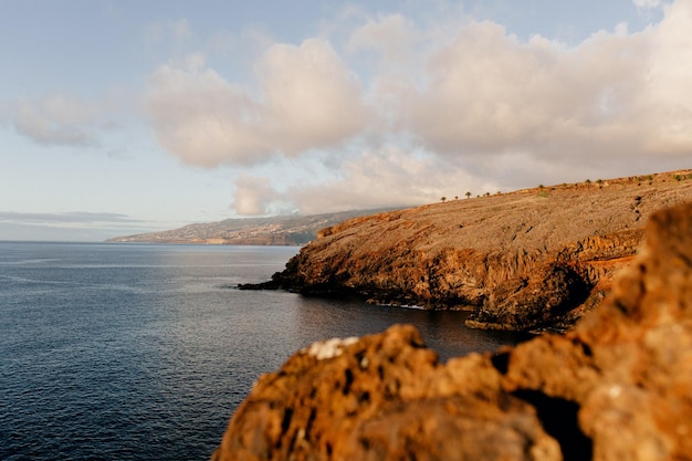 Free photo landscape of wide calm blue ocean with wild orange rocks at sunset power of nature freedom travel