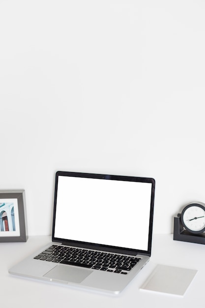 Laptop near table watch, photo frame and paper