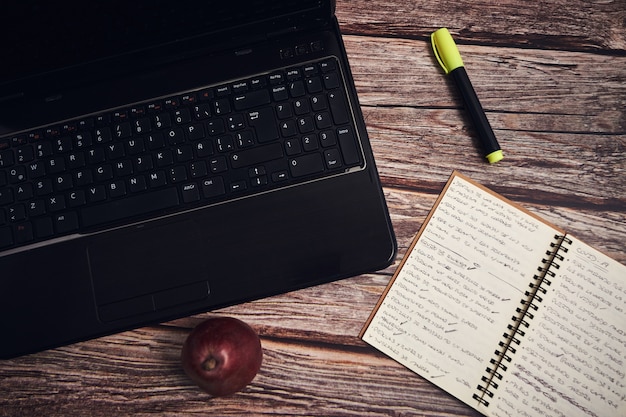 Free photo laptop and a notebook on a wooden desk