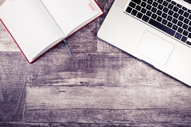 Free photo laptop and a notebook for writing from above view on a wooden background