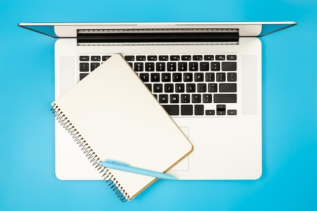 Free photo laptop and notepad on a blue background flat lay