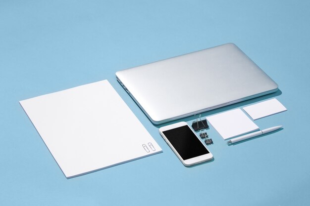 The laptop, pens, phone, note with blank screen on table