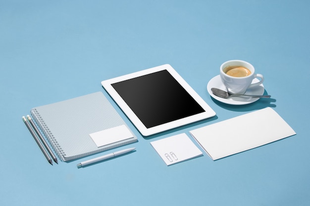 laptop, pens, phone, note with blank screen on table