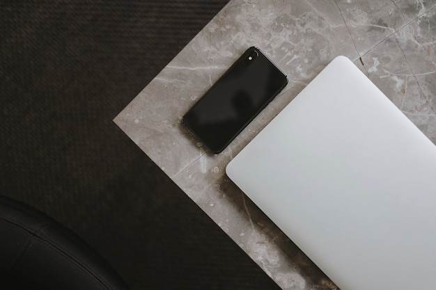 Laptop and a phone on a marble table