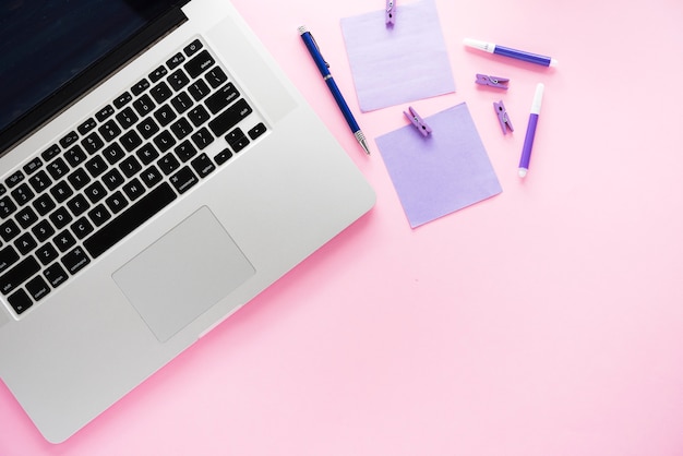 Laptop and supplies with pink background