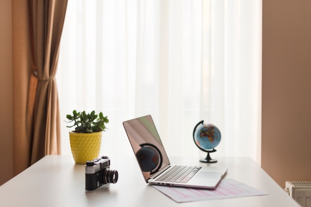 Laptop on table near camera and globe