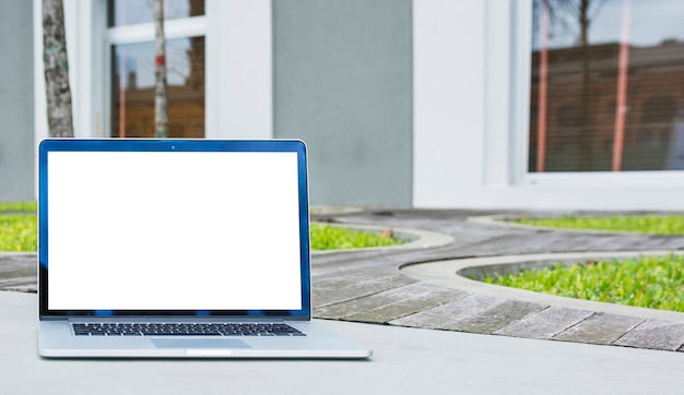 Free photo laptop with blank screen in front of house