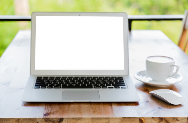 Laptop with blank screen on a wooden table and a cup of coffee