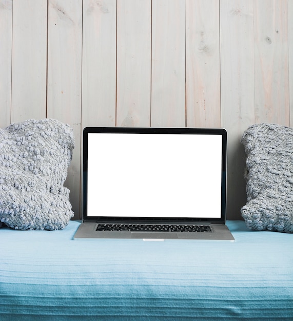 Free photo laptop with blank white screen and pillow on sofa