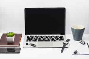 Free photo laptop with coffee cup and plant