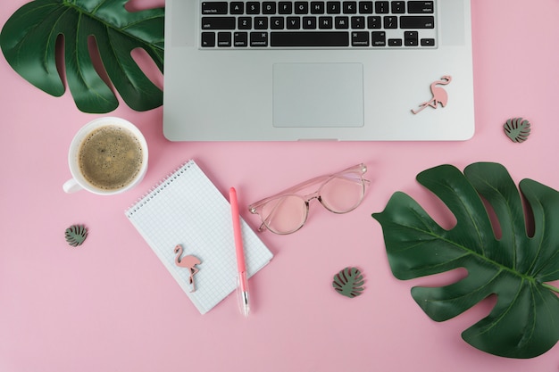 Laptop with notebook and small flamingos on table