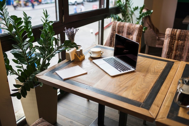 Free photo laptop with notepad in cafe on table