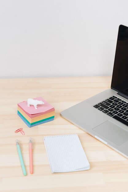 Laptop with notepad on wooden table