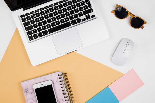 Laptop with smartphone and mouse on table