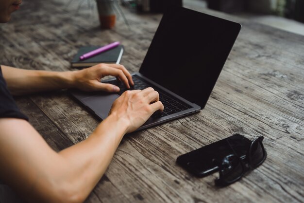 laptop on a wooden table, hands of a man working on a computer