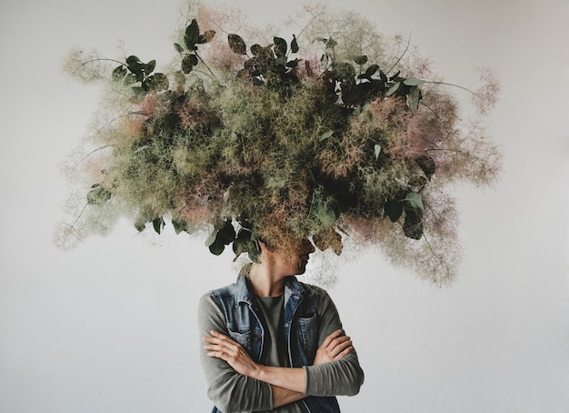 Large decorative bouquet made of green leaves and moss hangs over man's head