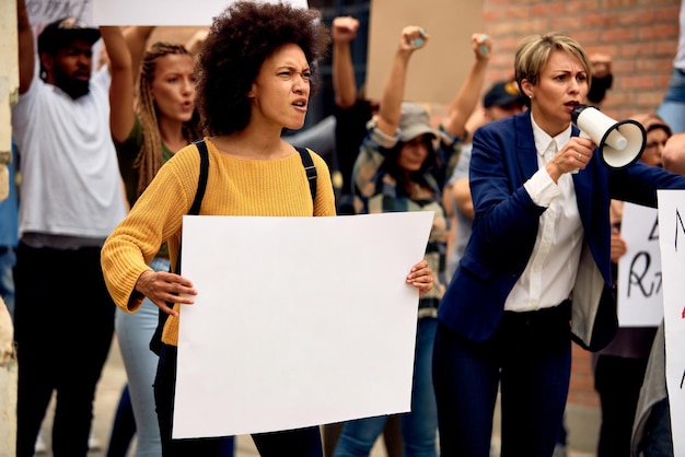 Free photo large group of displeased protesters marching at demonstrations on the streets focus is on african american woman holding blank placard copy space