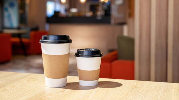 Large and small cup of coffee on a wooden table in a cafe. Recycling idea